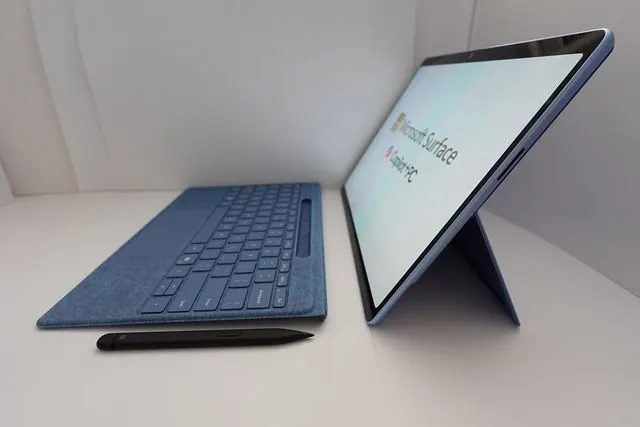 Une tablette Microsoft Surface posée sur sa béquille, à côté de son clavier détaché et d'un stylet.