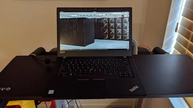 Un Lenovo ThinkPad T480 noir ouvert sur un bureau, avec son petit point rouge au milieu du clavier.
